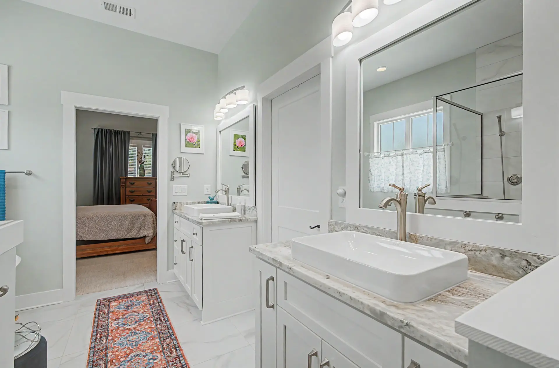 Primary bathroom with dual vanities, vessel sinks, and marble-look tile